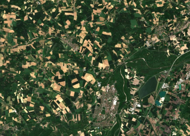 Satellite view of a rural landscape with agricultural fields A satellite image showing a rural landscape with green and yellow agricultural fields, roads, and a lake