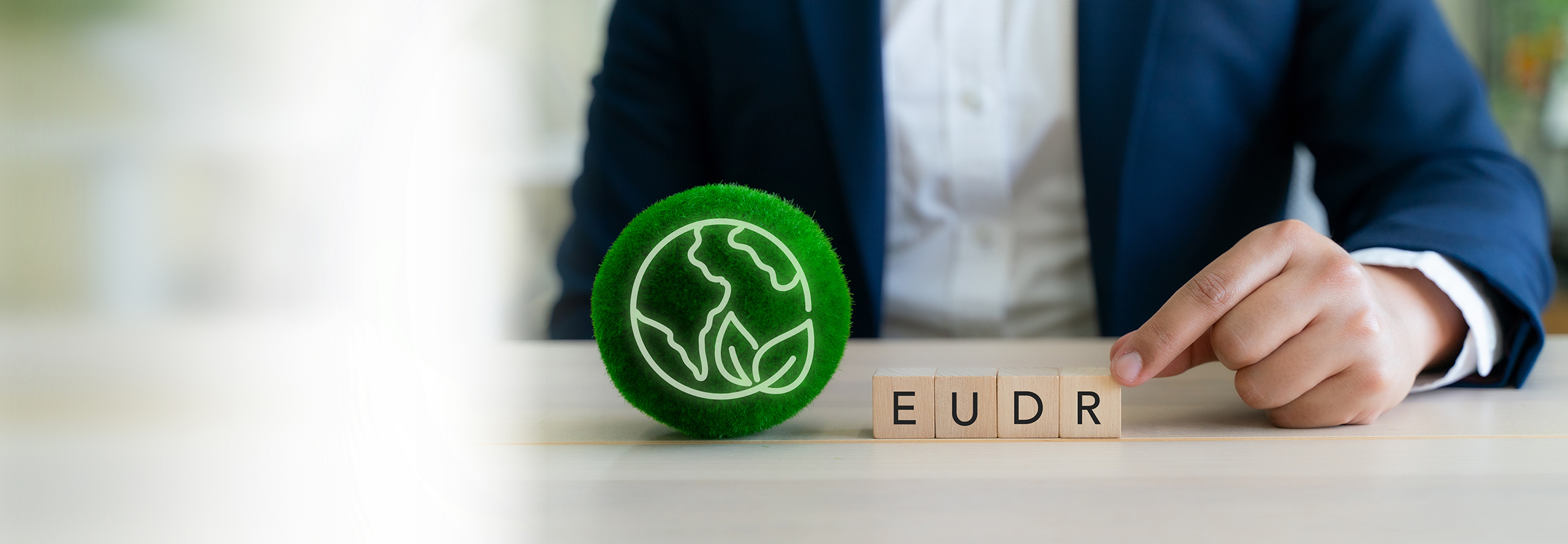 EUDR Environmental Responsibility Concept. EU Deforestation Regulation (EUDR). Wooden blocks spelling "EUDR" beside a green globe icon. Sustainable practices and corporate environmental responsibility